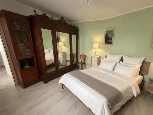 a bedroom with a large white bed and a mirror at Casa di Paola Spormaggiore in Spormaggiore