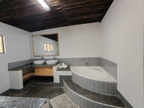 a bathroom with a tub and a sink and a mirror at Masango Lodge in Hoedspruit