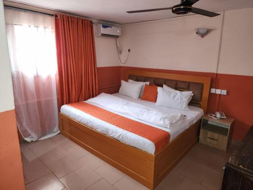 a bedroom with a large bed with an orange and white bedspread at Zim Zam View Hotel in Onitsha