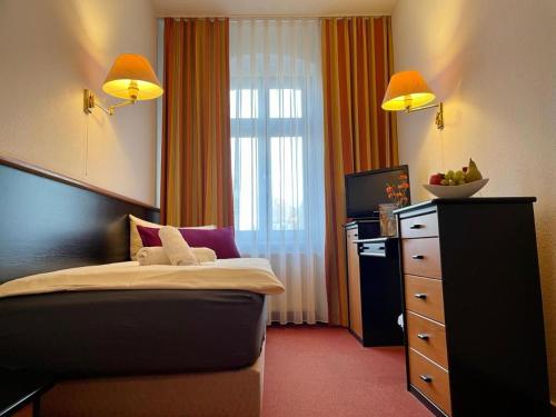 a bedroom with a bed and a dresser with a television at Hotel an der Rennbahn Kostenloses Parken in Dresden