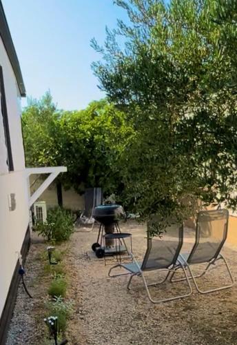 a backyard with chairs and a grill and a tree at MARIS MOBILE HOME in Drage