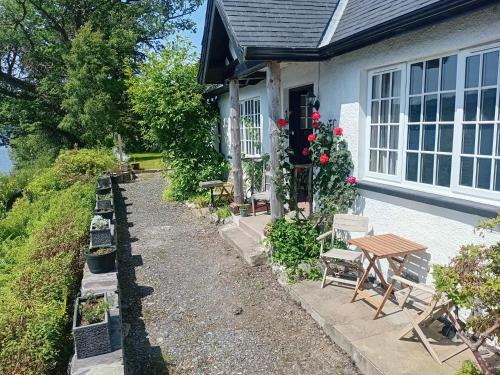 a house with chairs and a table in front of it at Ardross Cottage in Aberfoyle