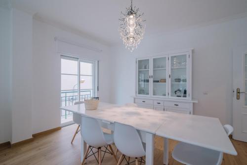 a white dining room with a white table and chairs at Casa do Jardim in Olhão