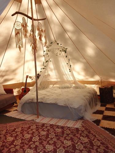 a canopy bed in a tent with a rug at Glempings Pasaka un pirts I tent and sauna in Vecumnieki