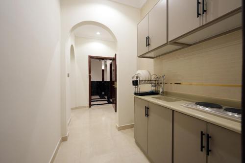 a kitchen with white cabinets and a sink and a hallway at فندق النخبة البلاتيني - Platinum Elite Hotel in Medina