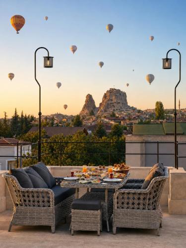 a patio with a table and chairs and hot air balloons at Üçhisar Palace İn Cappadocia in Uçhisar