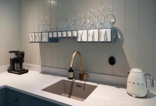 a kitchen counter with a sink and glasses on shelves at Østigård 1810 Prestegårdshuset in Åndalsnes