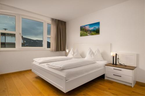 a white bedroom with a bed and two windows at Residence Diana Apartment 402 in Terento