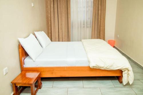 a bed with white sheets and a table in a room at Royce's Apartment in Kigali