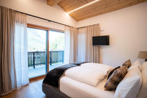 a bedroom with a bed and a large window at Ciasa Verena in Corvara in Badia