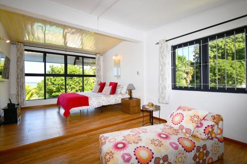 a bedroom with a bed and a couch and windows at Villa Antema in Riambel