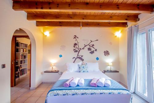 a bedroom with a bed with pillows and a tree on the wall at Paxos Santa Marina Villas in Gaios