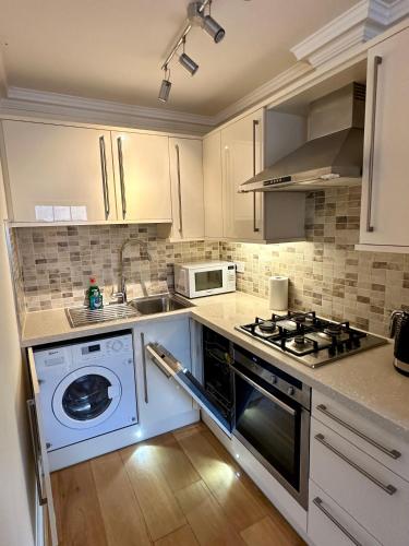 a kitchen with a stove and a washer and sink at Russell Square Beautiful Quality Apartment in London