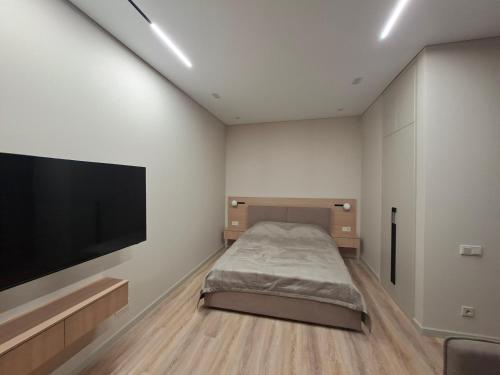 a bedroom with a bed and a flat screen tv at Central Avenue in Karagandy