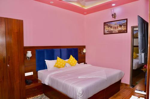 a bedroom with a large white bed with yellow pillows at Hotel Cyra palace in Jaipur