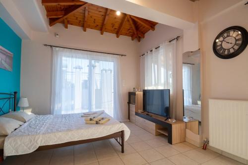 una camera da letto con un letto, una tv e un orologio di SkyView Loft a Kalamáta