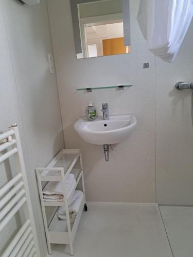 a white bathroom with a sink and a mirror at Ferienwohnung Kirschbaumblick in Ettringen