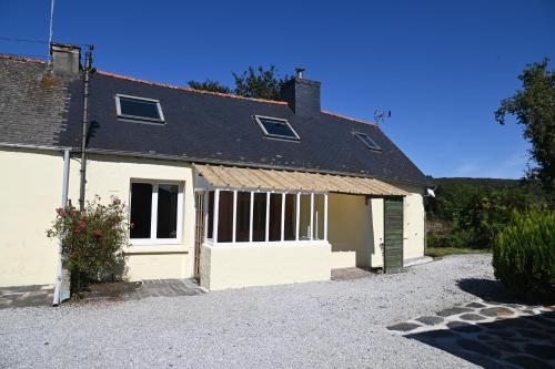 a white house with a garage and a driveway at Keriven Cottage in Caurel