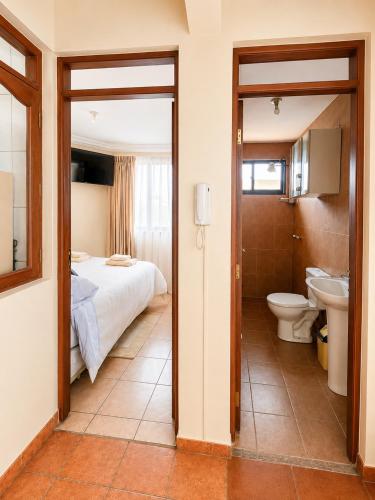 a bedroom with a bed and a toilet and a sink at Hipódromo Sky Penthouse in Cochabamba