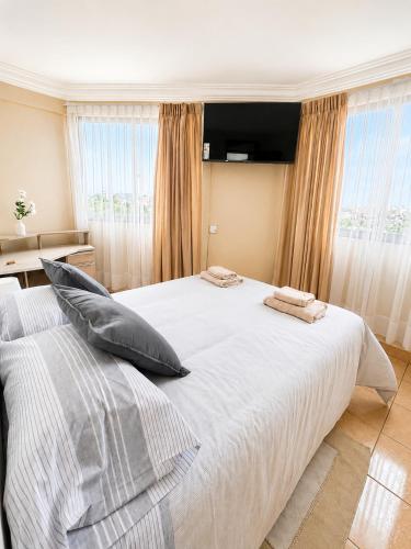a bedroom with a large white bed with pillows on it at Hipódromo Sky Penthouse in Cochabamba