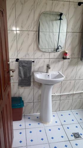 a bathroom with a white sink and a mirror at Velo Apartments in Kribi in Kribi