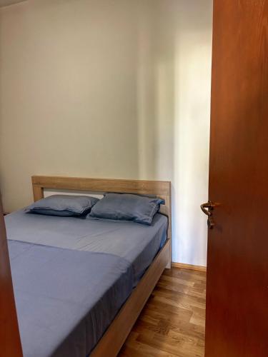 a bed with blue pillows sitting next to a door at L&K Old Town Apartment in Podgorica