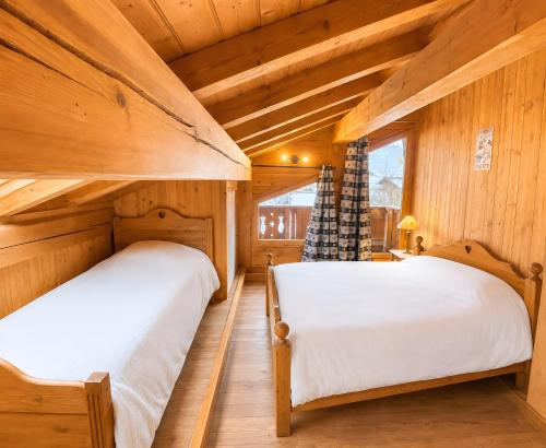 two beds in a room with wooden walls at Les Dolomites in La Plagne Tarentaise