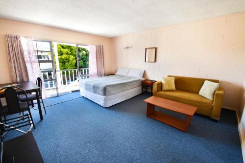 a bedroom with a bed and a couch and a window at Union Victoria Motel in Rotorua