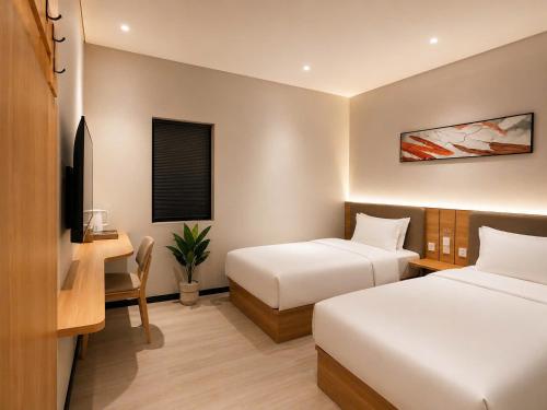 a hotel room with two beds and a desk and a tv at Hotel 7 Days Duc Hoa in Ấp Bình Tả (2)