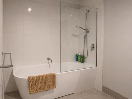 a white bathroom with a shower and a bath tub at 18 Pimpama Home in Pimpama