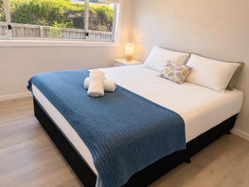 a bedroom with a bed with a blue blanket and a window at 18 Pimpama Home in Pimpama