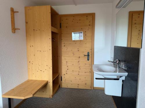a bathroom with a wooden door and a sink at Stöcki-Grindelwaldblick in Kleine Scheidegg