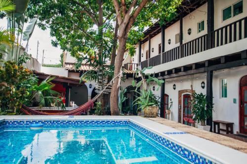 
a large swimming pool with a large tree in front of it at Island Life Hostel in Santo Domingo

