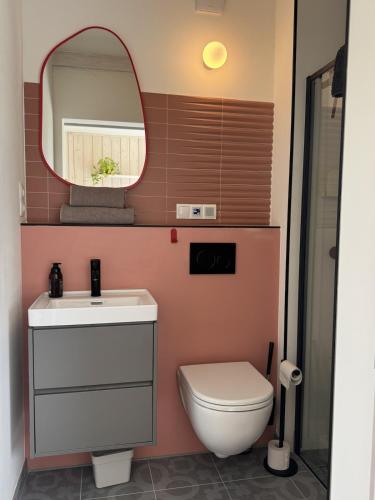 ein Badezimmer mit weißer Toilette und Spiegel in der Unterkunft Homemade Studio in Liebshausen