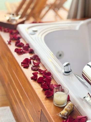 a bathroom counter with roses and a candle and a bath tub at Cabana Refúgio Barn in Caxias do Sul