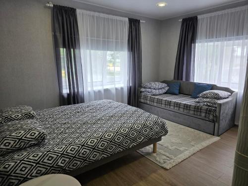 a bedroom with a bed and a couch and windows at Mustvee aparts in Mustvee