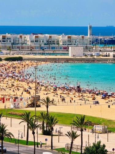 a beach with a large crowd of people in the water at panoramic sky 17 in Tangier