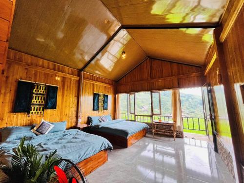 two beds in a room with wooden walls and windows at Peaceful Happiness Bungalow with Valley Views in Sapa