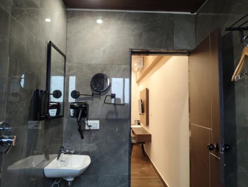 a bathroom with a sink and a mirror at Gamagashree Hotel and Fine Dine in Sāgar