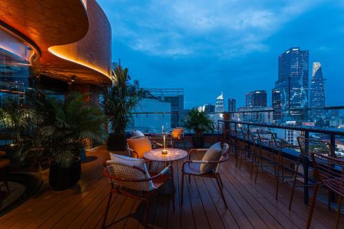 a balcony with chairs and tables and a city skyline at KiN Hotel Ly Tu Trong Edition in Ho Chi Minh City