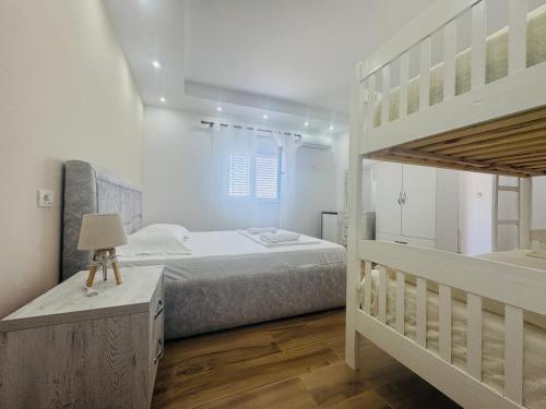 a white bedroom with a bunk bed and a ladder at Restorant Hotel Niku in Draç