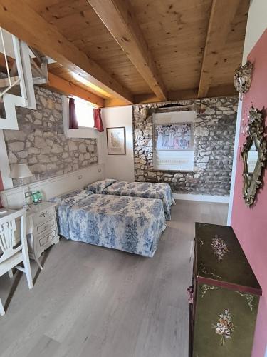 a bedroom with a bed and a stone wall at Talamo Rooms in San Martino Buon Albergo