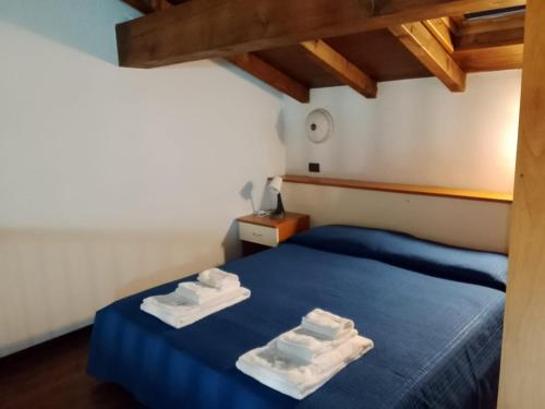 a bedroom with a blue bed with towels on it at Mulinaccio Appartamenti in Pievepelago