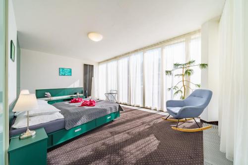 a bedroom with a bed and a blue chair at Spa Sanatorium Dr Peták in Františkovy Lázně