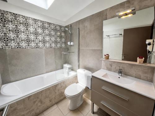 a bathroom with a toilet and a tub and a sink at Hotel Saint Germain in Pézenas