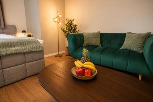 a living room with a green couch and a bowl of fruit at Schängel Chic 26 in Koblenz