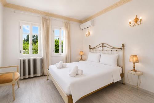 a white bedroom with a large white bed with two pillows at Villa Cypress with Private Pool and Mountain Views in Andros