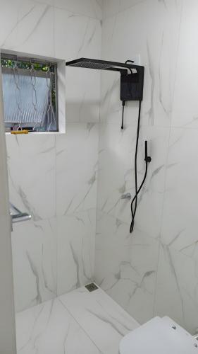 a white bathroom with a shower and a toilet at Dourados Guest Flat House in Dourados