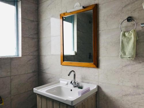 a bathroom with a sink and a mirror at Apple Flower Hotel - Personal Balcony, Lift, Garden and Mountain View in Manāli