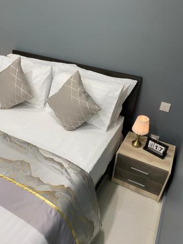 a bed with white pillows and a table with a lamp at Studio Apartment on a Terrace by Skysuites in Male City